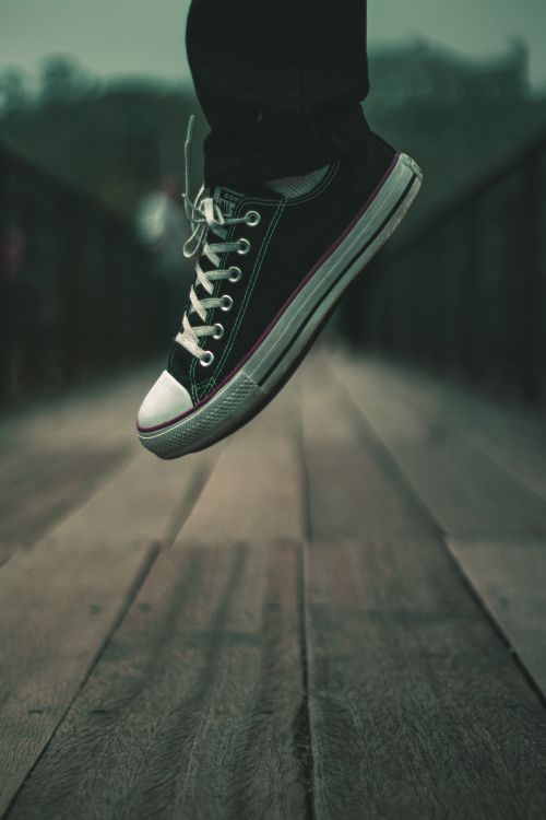 Free A person jumping with a sneaker on a wooden bridge, showcasing motion and style. Stock Photo