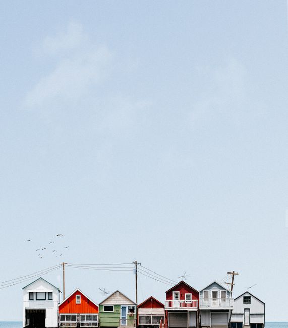 Vibrant coastal beach houses lined up against a clear blue sky, showcasing serene seaside charm.