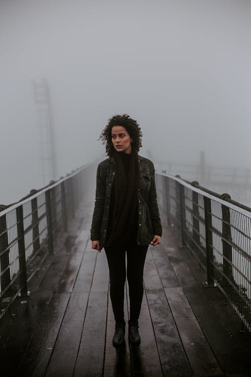 A Woman Wearing a Black Outfit Standing on a Bridge