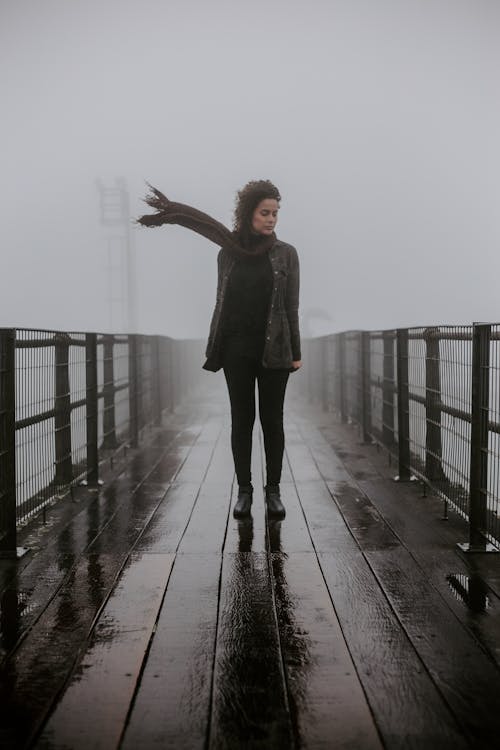 A Woman Wearing a Black Outfit Standing on a Bridge