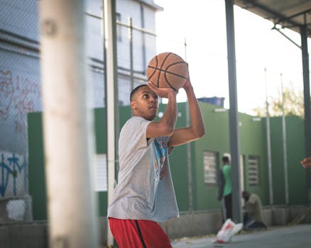 Young man shooting a basketball on an outdoor court, showcasing skill and focus.