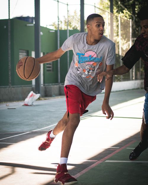 Free Energetic young man enjoying a game of basketball on an outdoor court in the sun. Stock Photo
