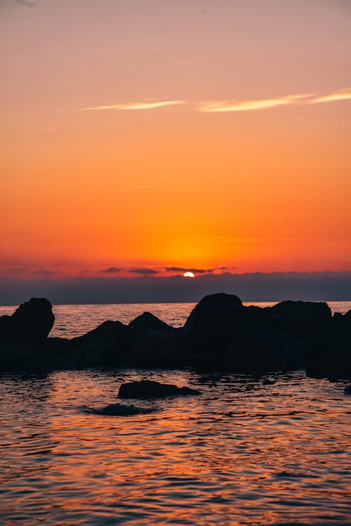 Silhouette of Rocks on the Sea during Sunset