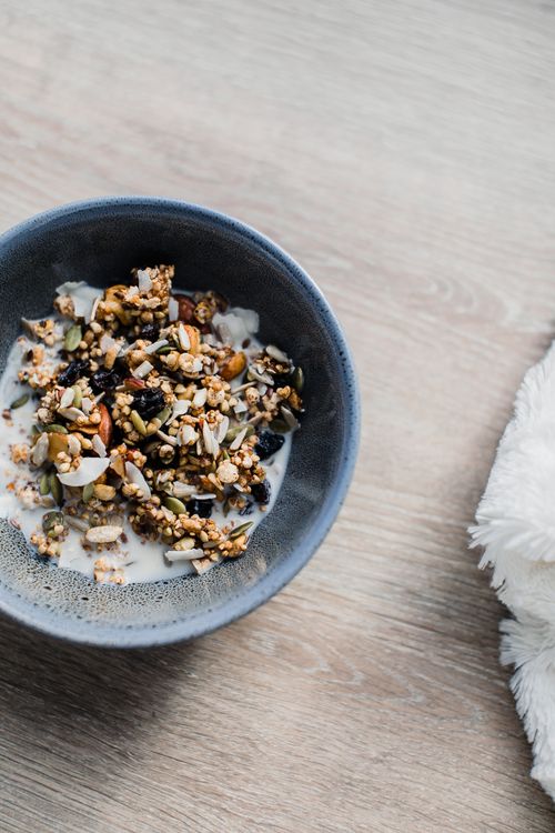 Free From above of tasty muesli with milk placed in gray bowl on wooden surface at home in morning time Stock Photo