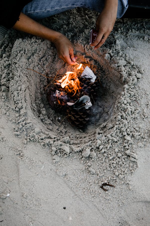 Person lighting fire on sandy beach