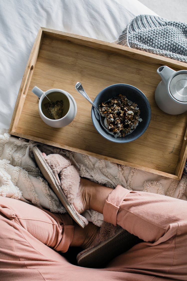 Woman Sitting On Bed With Breakfast On Tray