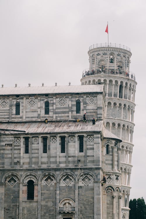 Leaning tower of Pisa and aged stone building of cathedral with ornamental details on walls