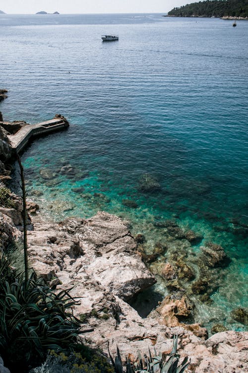 From above of rough stony shore of sea with rippling turquoise pure water