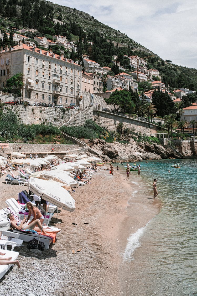 People Sunbathing On Sandy Beach