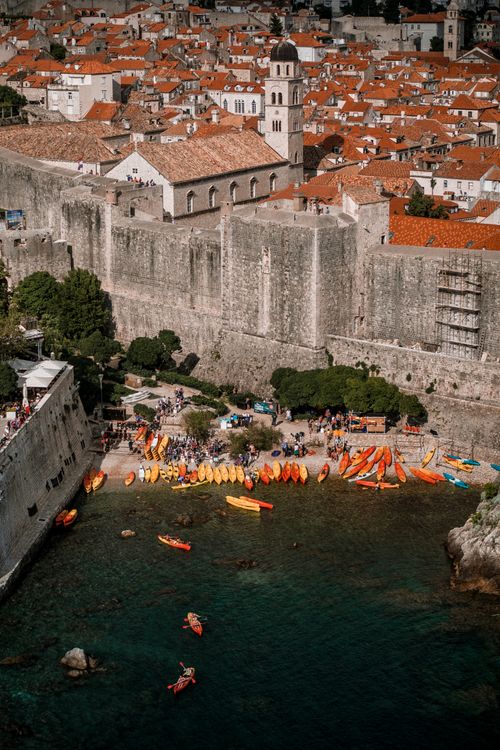 Free From above of colorful canoe boats on sandy shore of sea near stone building Stock Photo