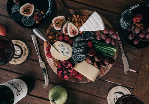 Free Top view of healthy delicious ripe fruits and nuts along with cheese on wooden tray near bottle of wine Stock Photo