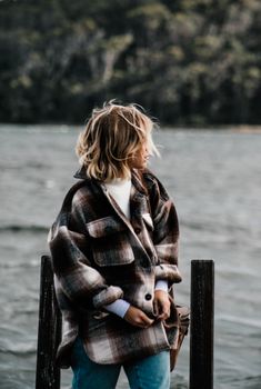 一名身穿休闲装的匿名女子站在码头边，望着波涛汹涌的水面