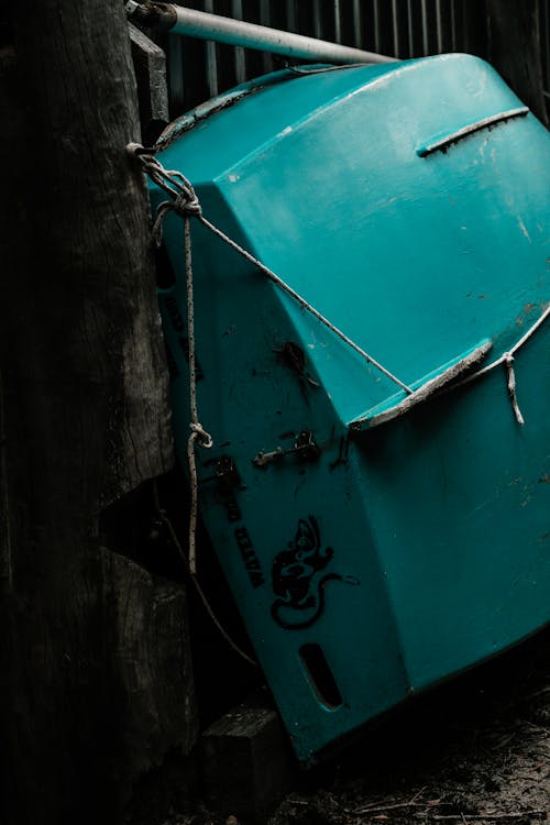 Free Small old shabby green row boat upside down placed near aged wooden construction Stock Photo