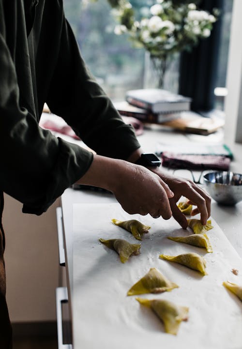 Crop unrecognizable person shaping Japanese dumplings gyozas while cooking in kitchen at home