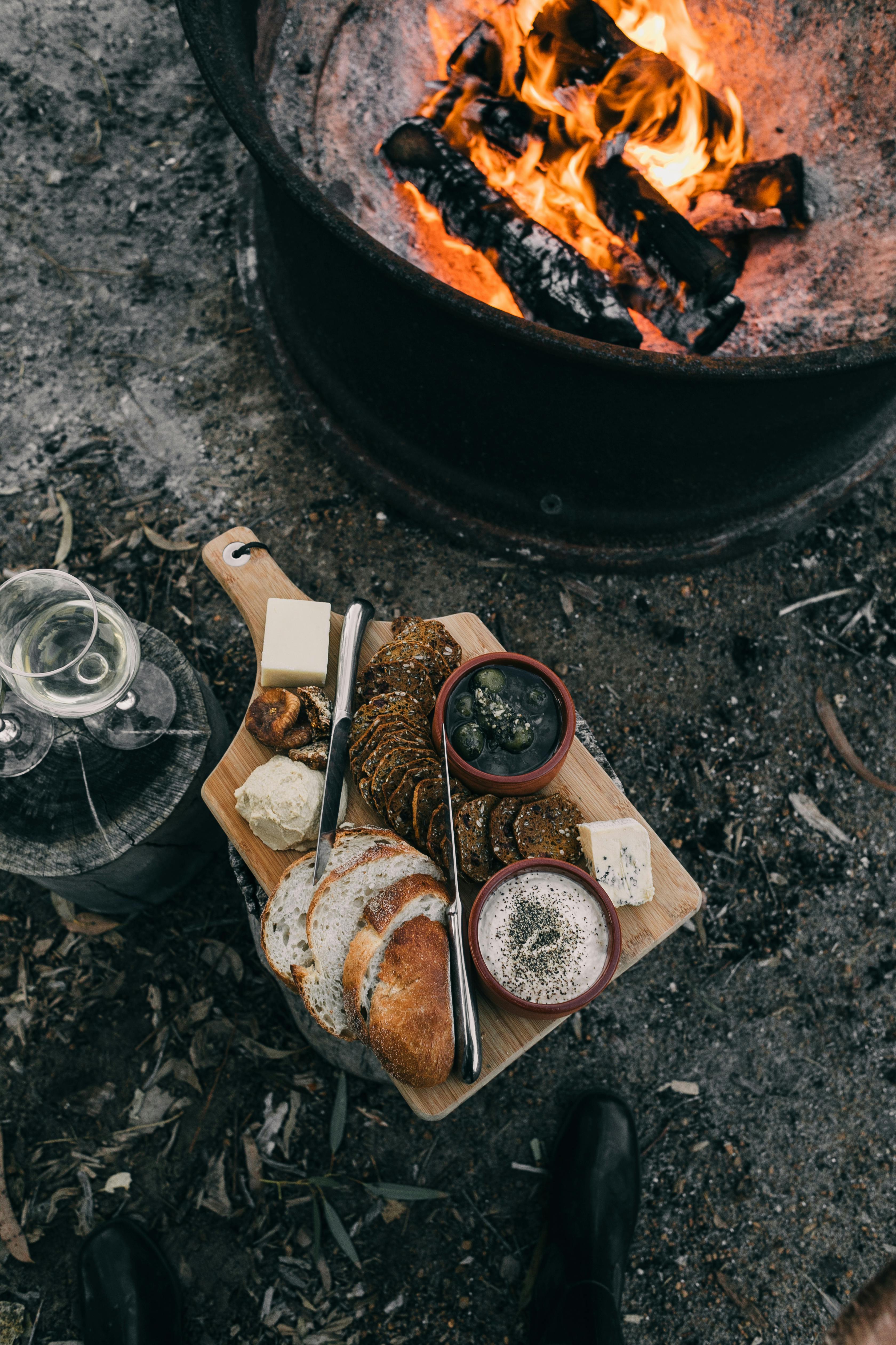 crop person near bonfire with food