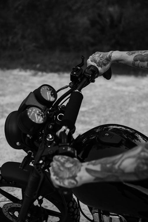 Free Unrecognizable male biker with tattooed hands riding vintage retro motorbike on rural road Stock Photo