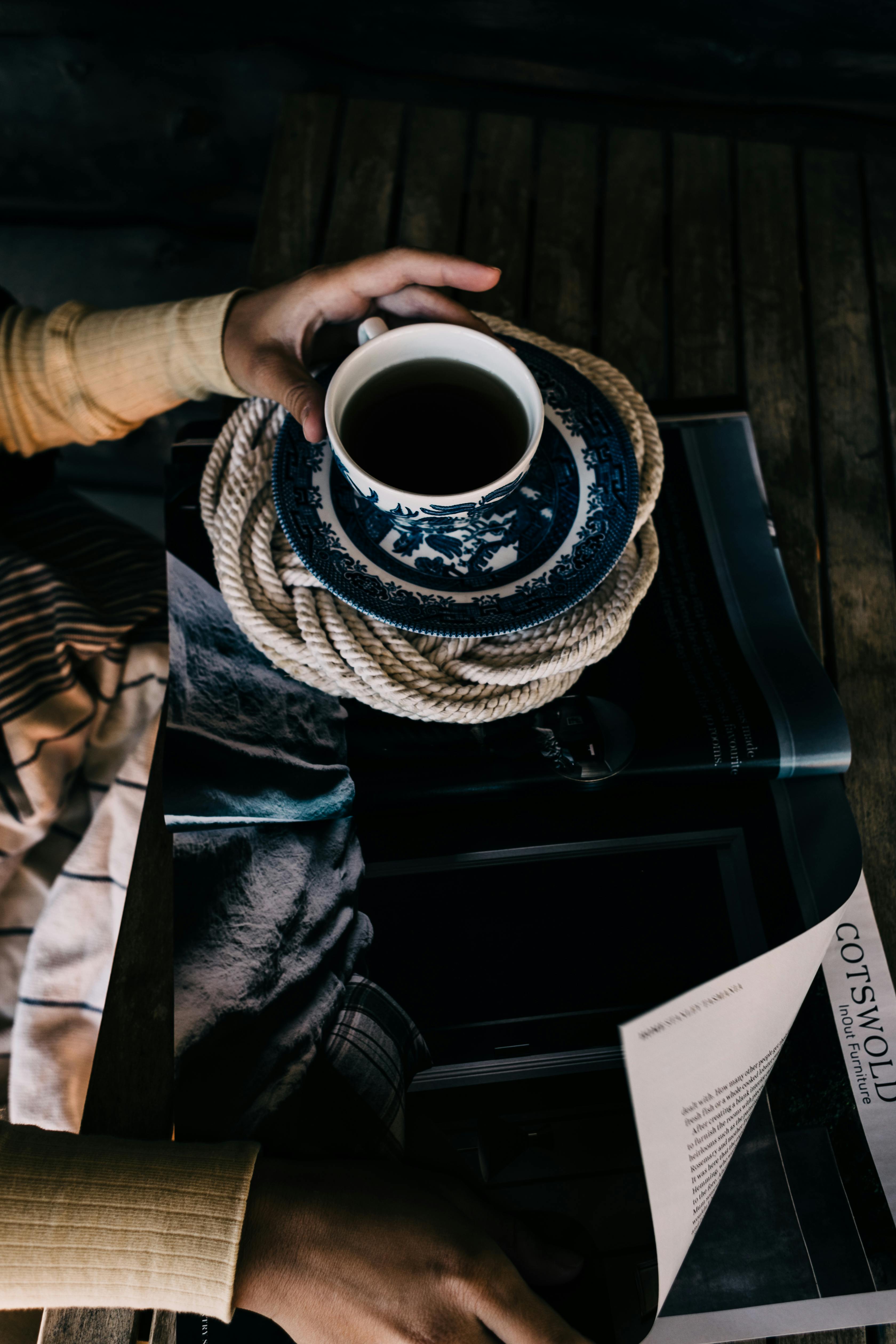 woman reading magazine while having hot beverage