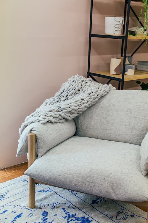 Armchair with plaid near shelves in room