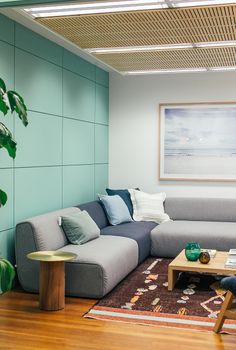 Light living room decorated with couch with pillows near table on carpet with painting on wall