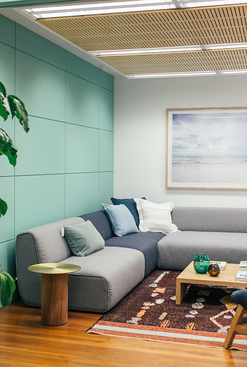 Free Light living room decorated with couch with pillows near table on carpet with painting on wall Stock Photo