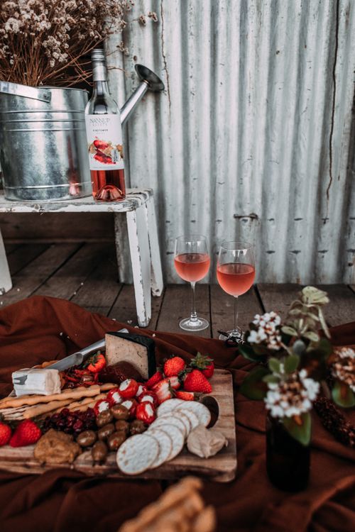 Free From above of wooden tray with pile of snacks and berries placed on soft plaid near glasses of wine Stock Photo