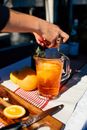 Crop anonymous female putting slices of orange into glass jar with fresh lemonade drink