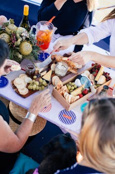 从上方俯瞰农田，一群没有面孔的人正在野餐，他们一边吃着奶酪和水果，一边喝着柠檬水和葡萄酒