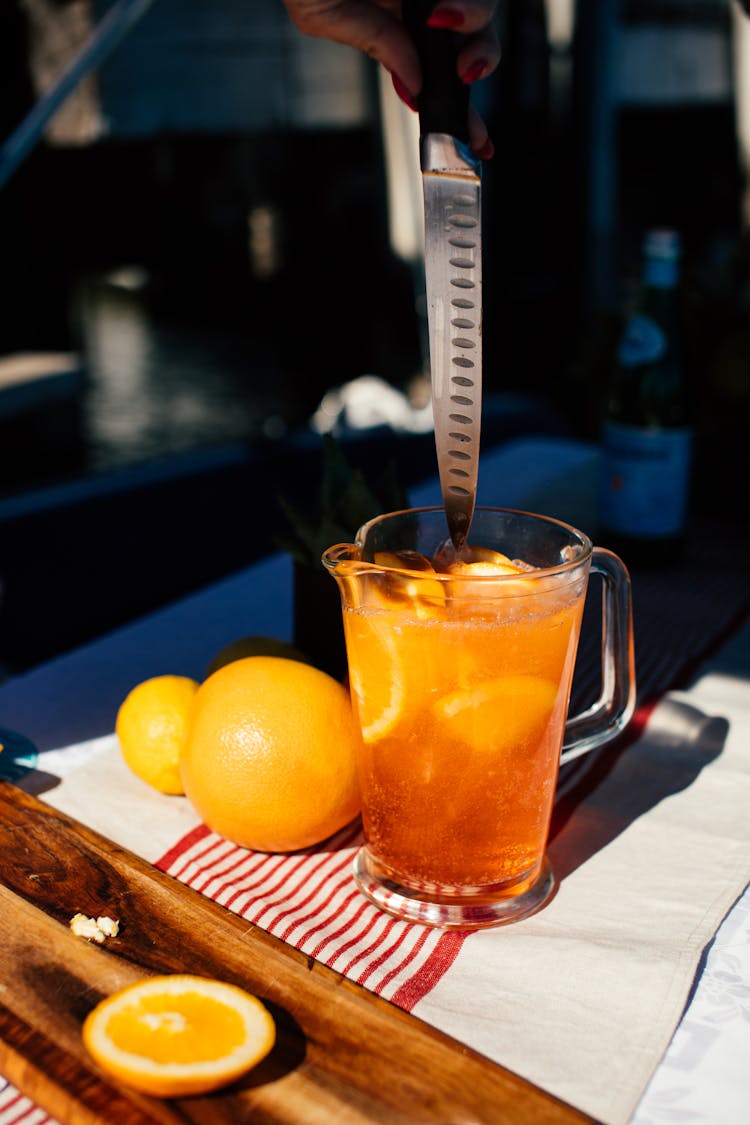 Crop Woman Stirring Drink With Orange