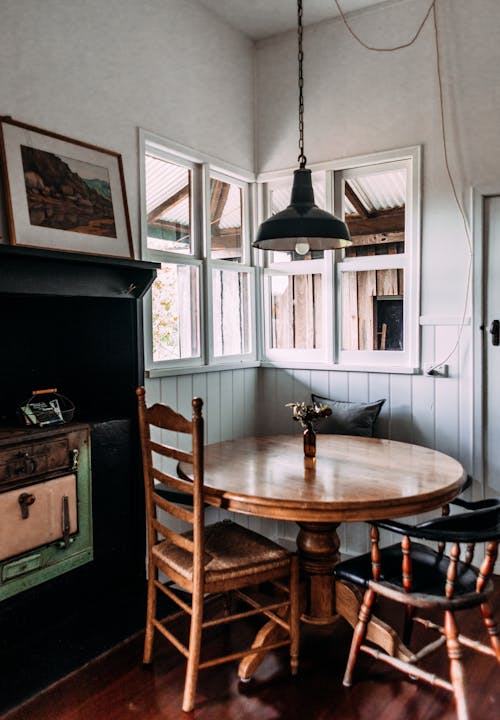 Round shaped table with flowers in vase against window and cabinet with picture at home