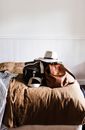 Hat on leather rucksack and travel bag on crumpled bed cover against white wall at home