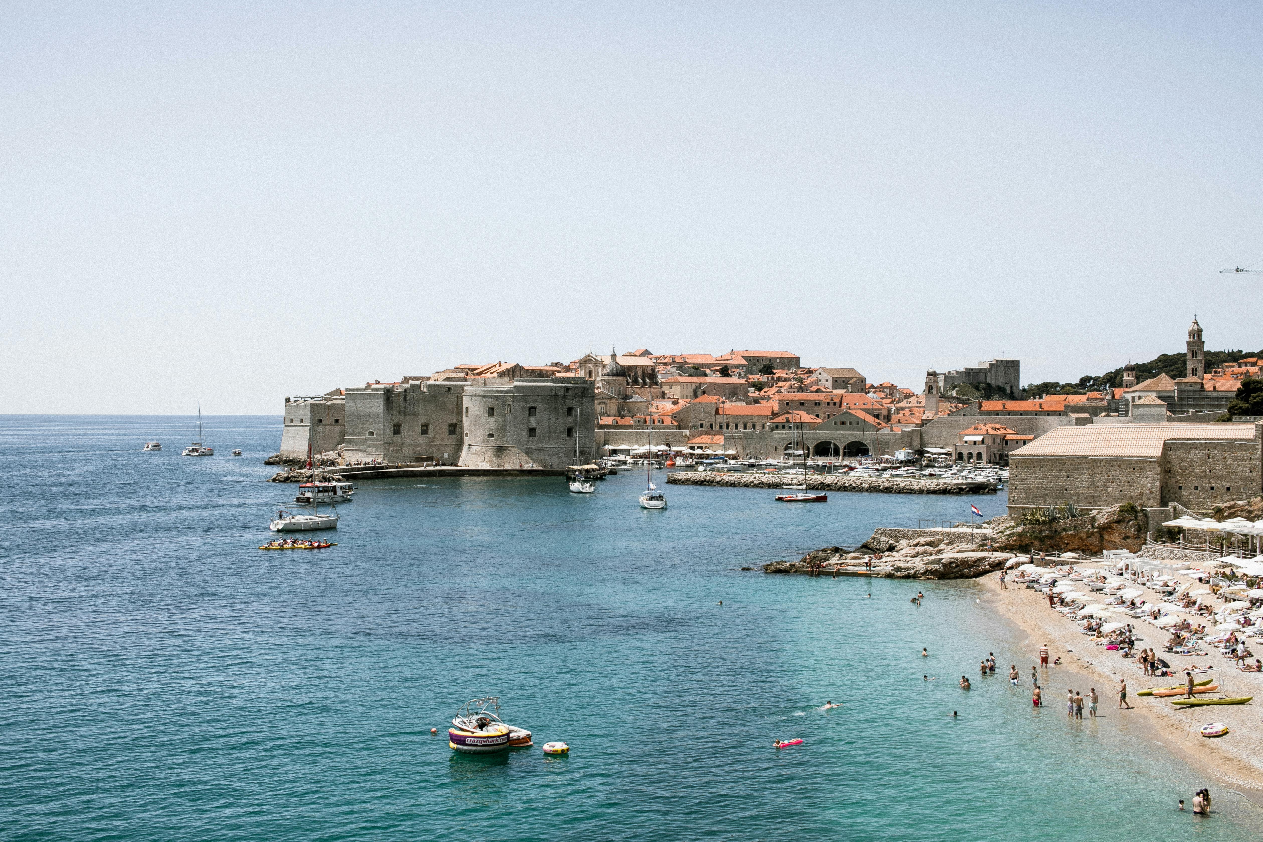 old stone fortress on shore with unrecognizable travelers against sea