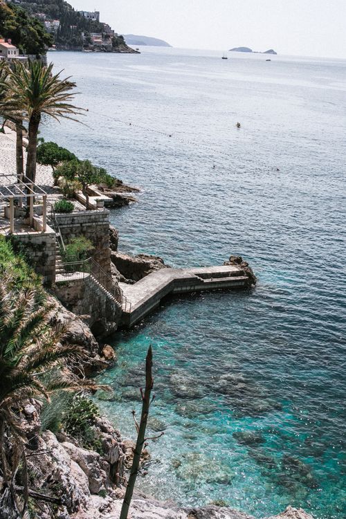 Free From above of aged dock in sea with pure rippled water against mounts and palm trees Stock Photo