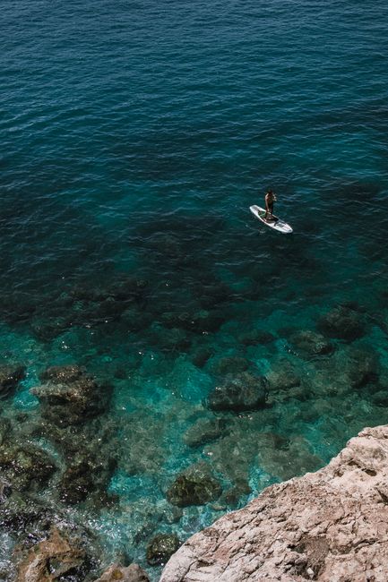 High angle of sailboat sailing on turquoise ocean with transparent water against mount in daylight