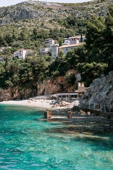 夏季，海岸与山脉之间，波光粼粼的大海风景如画，树木和建筑立面点缀其间