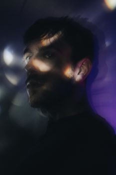 Artistic portrait of a man with light reflections creating a moody atmosphere.