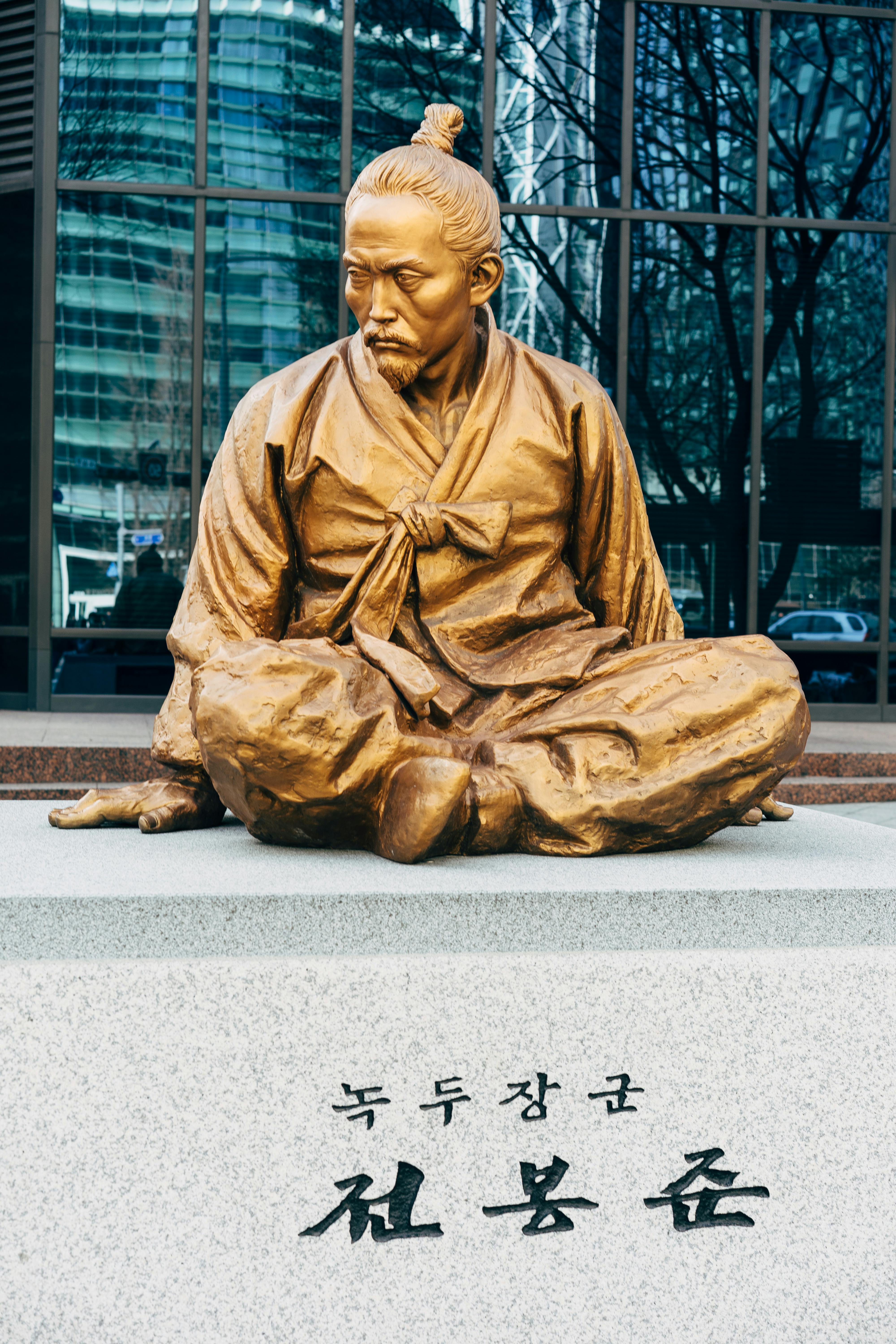 man in brown robe sitting on concrete bench