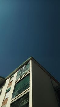 Low angle of contemporary exterior of house with glass balcony under clear blue sky