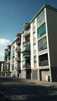 Low-angle view of a contemporary apartment building in Ravenna, Italy, under a clear blue sky.