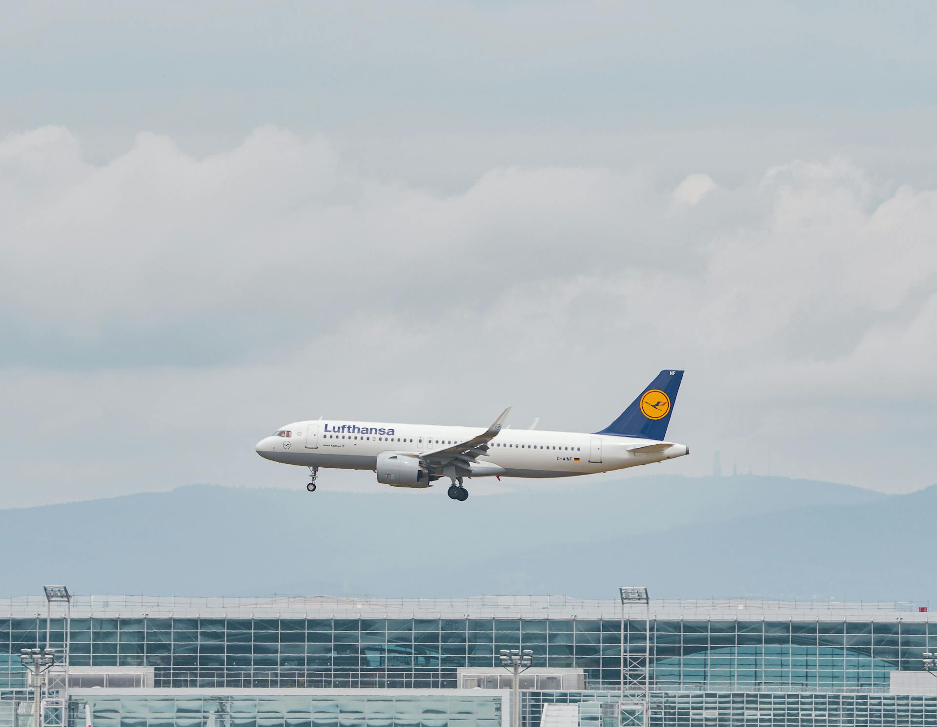 Lufthansa airplane approaching landing at Frankfurt Airport on a cloudy day.