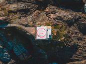 From above drone view of helicopter pad and road placed on edge of cliff in rocky highland