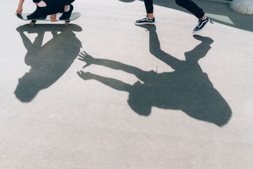 Free Silhouette of a skateboarder and running person casting a dramatic shadow. Stock Photo