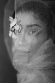 黑白肖像中，戴着面纱和鲜花的女子散发着优雅与神秘