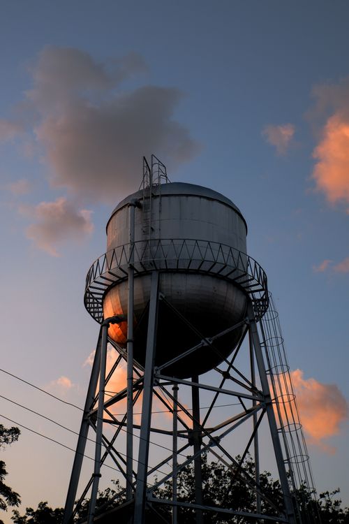 Free From below of industrial water tank on metal construction under blue cloudy sky at sundown Stock Photo