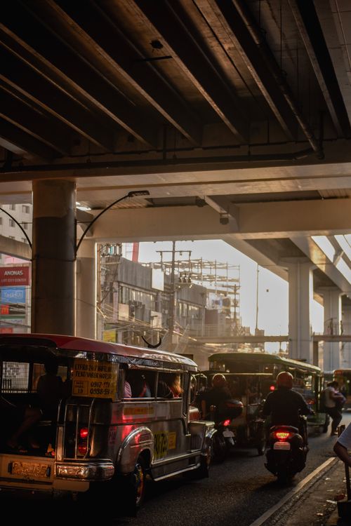 Free Back view of anonymous motorcyclists driving bikes near public transport on urban roadway under bridge and sky in evening Stock Photo