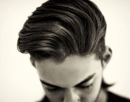 Close-up portrait of a fashionable man showcasing a sleek hairstyle in a black and white studio shot.