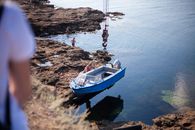 White and Blue Boat on Brown Rock Formation Near Body of Water
