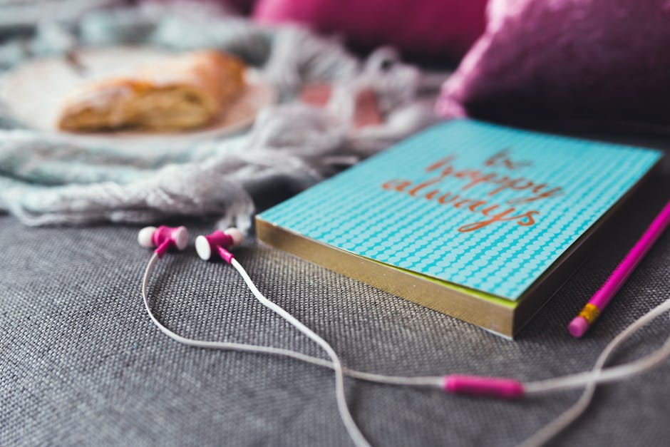 White and Pink Earphones on Gray Textile