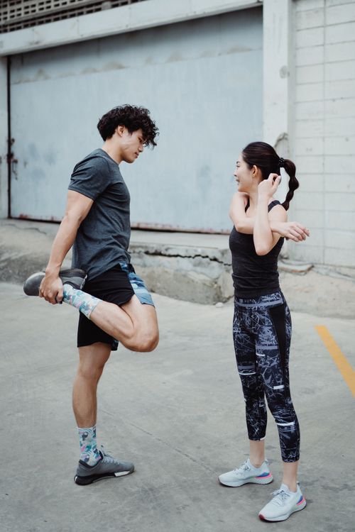 Free Two people stretching in sportswear outdoors, preparing for exercise with enthusiasm. Stock Photo