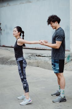 A young couple practicing stretching exercises outdoors in an urban area.