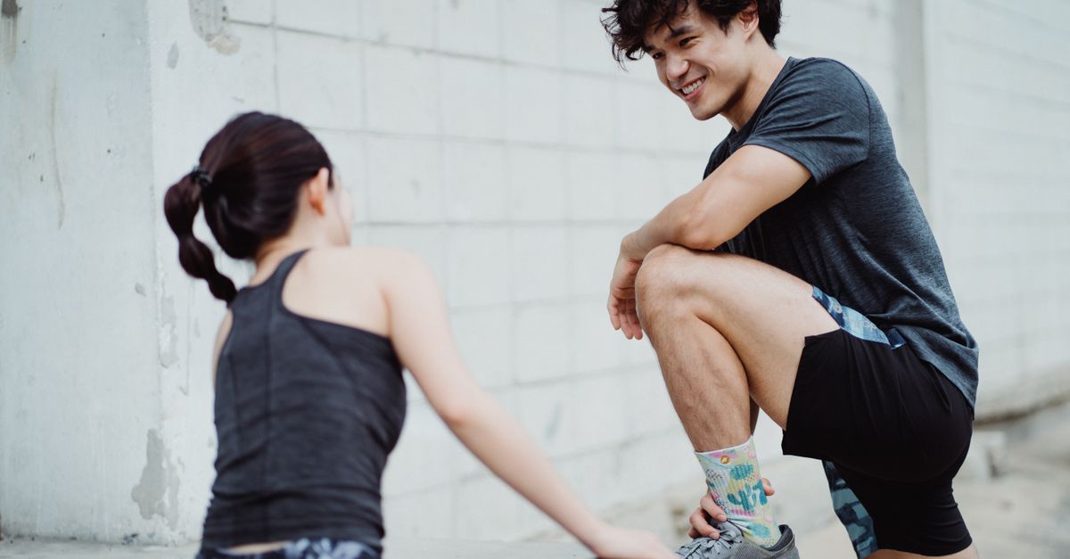 A man and woman interacting during an outdoor workout session, promoting healthy lifestyle.